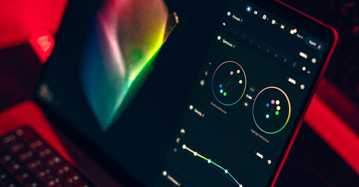 A laptop in a dark studio displaying a color-grading dashboard with spectrum controls — the design work AI image generators automate for YouTube thumbnails