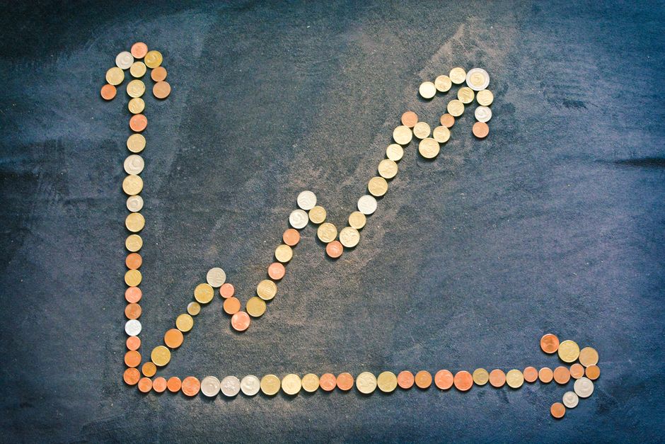 Coins arranged in a rising growth chart representing high-RPM faceless YouTube niches that pay $10 to $55 per 1,000 views